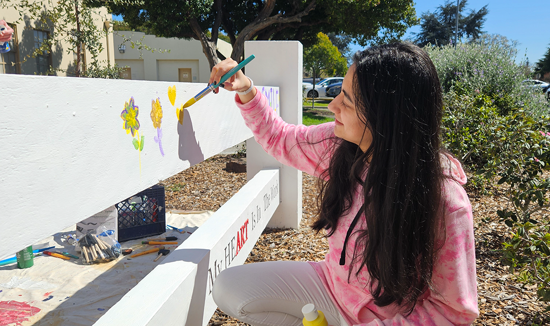 student paints fence at CMU-SV